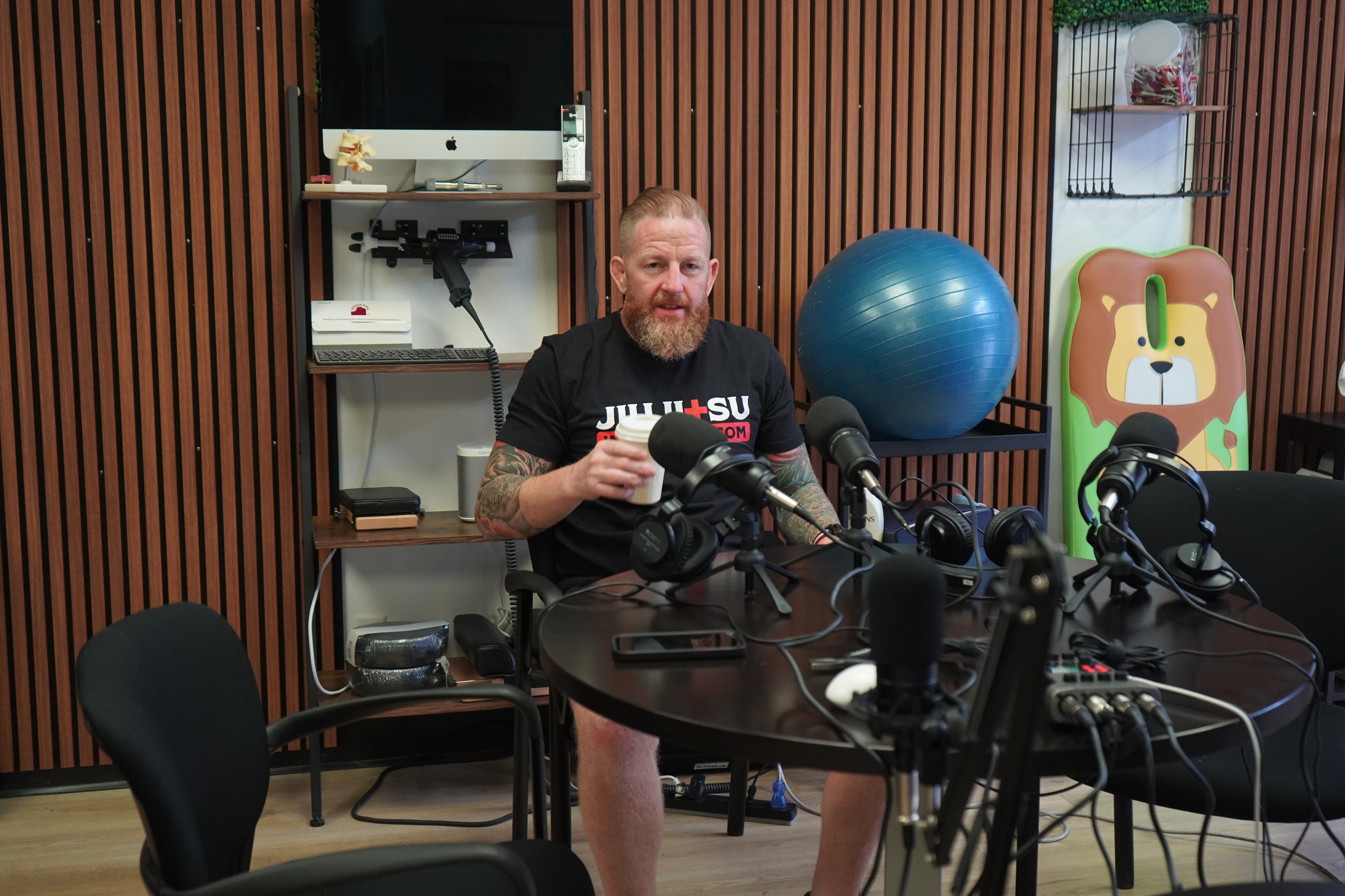 Chris Martin recording a podcast episode — Jiu Jitsu Insurance shirt, studio setup